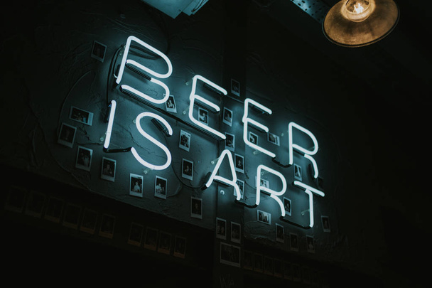BRIGHTON, ENGLAND - October 26th, 2018: A Beer is Art neon lettering lights in a wall at night, in blue color, with blue color, inside a pub in the city center of Brighton, England. - Foto, Imagen