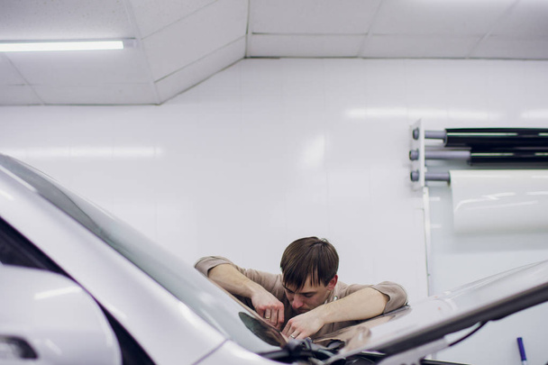 Worker hands installs car paint protection film. - Photo, image