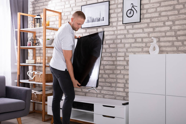 Young Man Placing New Television At Home - Фото, изображение