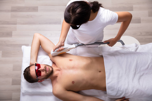 Close-up Of Smiling Young Man Having Underarm Laser Hair Removal Treatment In Spa - Zdjęcie, obraz