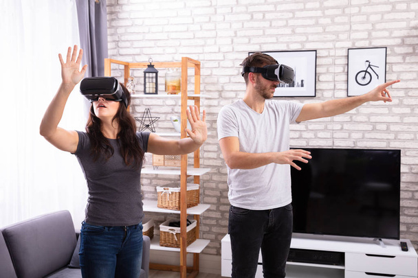 Young Couple Using Virtual Reality Device At Home - Φωτογραφία, εικόνα