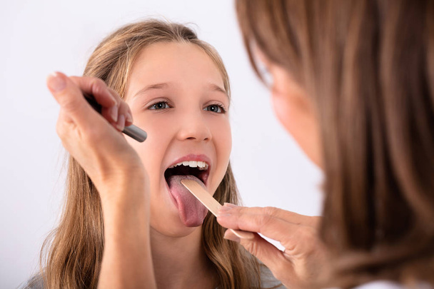 Close-up Of Doctor Checking Girl's Sore Throat With Tongue Depressor - Foto, imagen