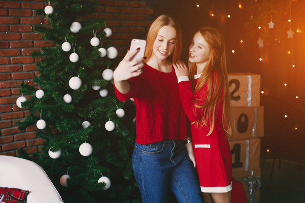 kaksi kaunista ja söpöä siskoa juhlivat joulua kotona
  - Valokuva, kuva