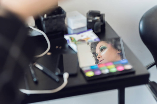 Reflexion des schönen Make-up-Modells im Spiegel der bunten Lidschattenpalette  - Foto, Bild
