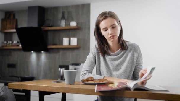 Young woman reading magazine near cup at table  - Filmmaterial, Video