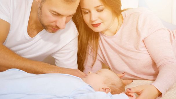 Glückliche Eltern blicken auf süßes schlafendes Baby im Schlafzimmer. - Foto, Bild