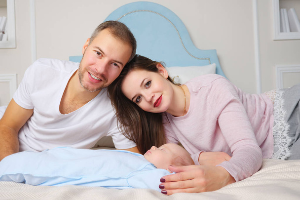 Szczęśliwych rodziców, leżąc na łóżku miękkie w pobliżu słodkie dziecko śpi w stylowej sypialni - Zdjęcie, obraz