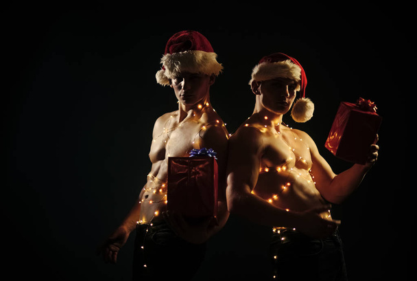 Young men in santa costume, present for girls. - Zdjęcie, obraz