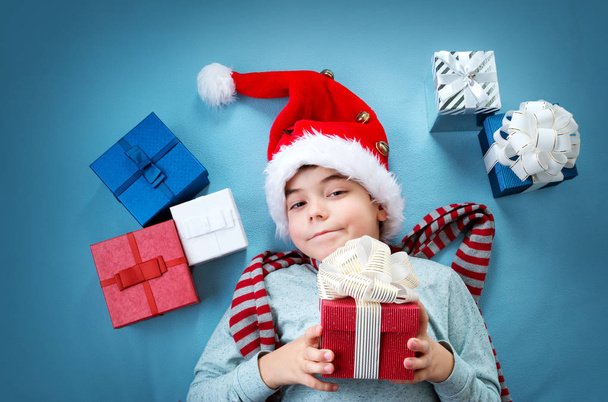 Smiling boy on red blanket with presents - Foto, Bild