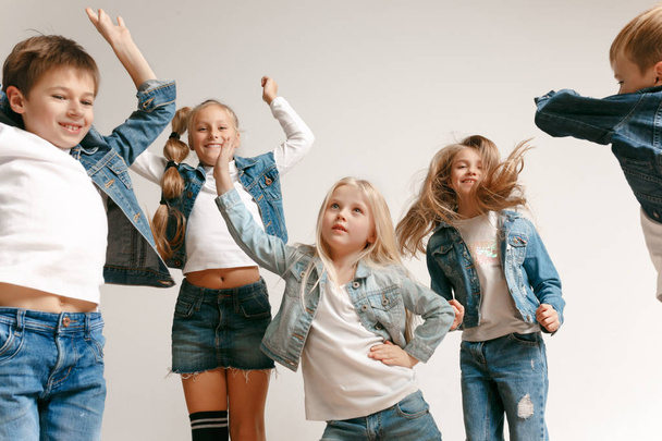 The portrait of cute little boy and girls in stylish jeans clothes looking at camera at studio - Foto, Imagem