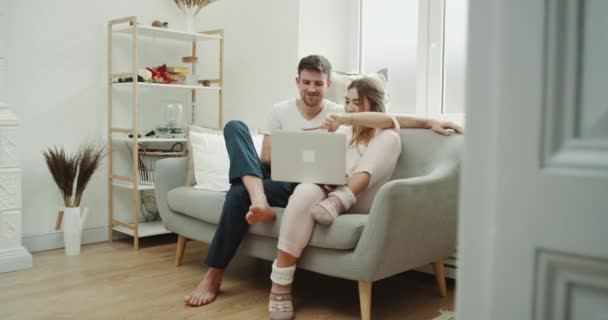 In the modern living room couple using a notebook order something and using a phone to make confirmation of order. - Кадры, видео