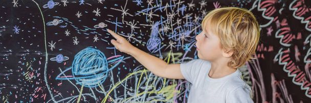 Little boy pointing painted space, planets and stars on wall.  - Zdjęcie, obraz