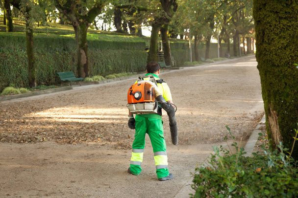 Zahradník s batohem ventilátor pracuje v městském parku, foukání lístečky. Podzimní koncept - Fotografie, Obrázek