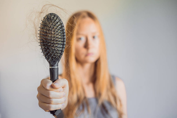 Hair loss in women concept. A lot of lost hair on the comb. - Foto, Bild