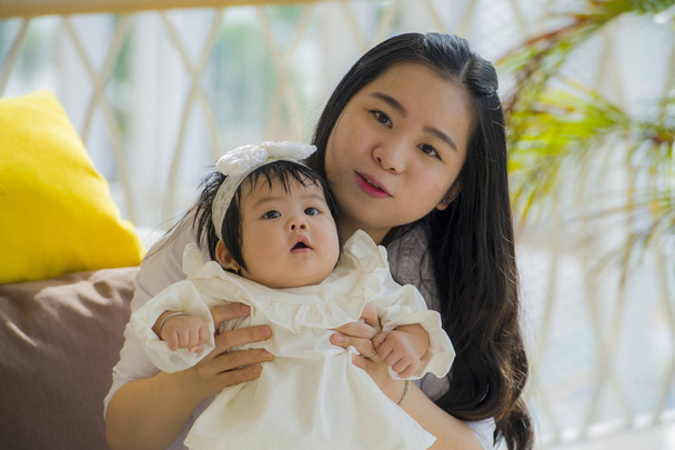 young happy and cute Asian Korean woman playing and holding sweet adorable baby girl sitting at holidays resort enjoying summer vacation trip in mother and little daughter love concept  - Foto, afbeelding