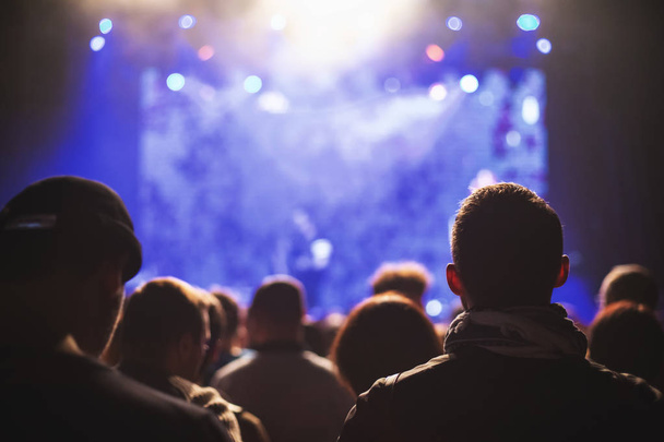 Sziluettek a koncert előtt egy megvilágított színpadon, egy szórakozóhely tömeg. - Fotó, kép