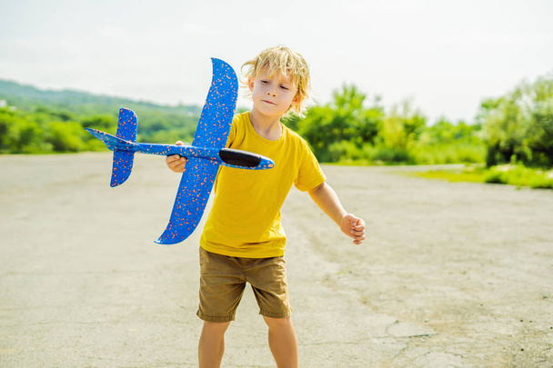 Happy kid playing with toy airplane against old runway background. Traveling with kids concept. - Фото, изображение