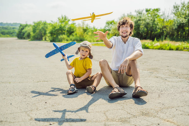 Happy father and son playing with toy airplane against old runway background. Traveling with kids concept. - Foto, Imagen