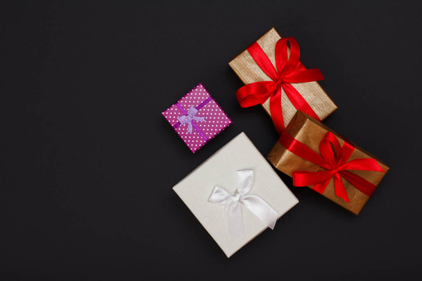 Cajas de regalo atadas con cintas sobre fondo negro. concepto de tarjeta de felicitación. Vista superior con espacio de copia
. - Foto, Imagen