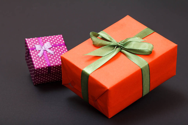 Geschenkboxen mit grünen und roten Bändern auf schwarzem Hintergrund gebunden. Festtagskonzept. - Foto, Bild