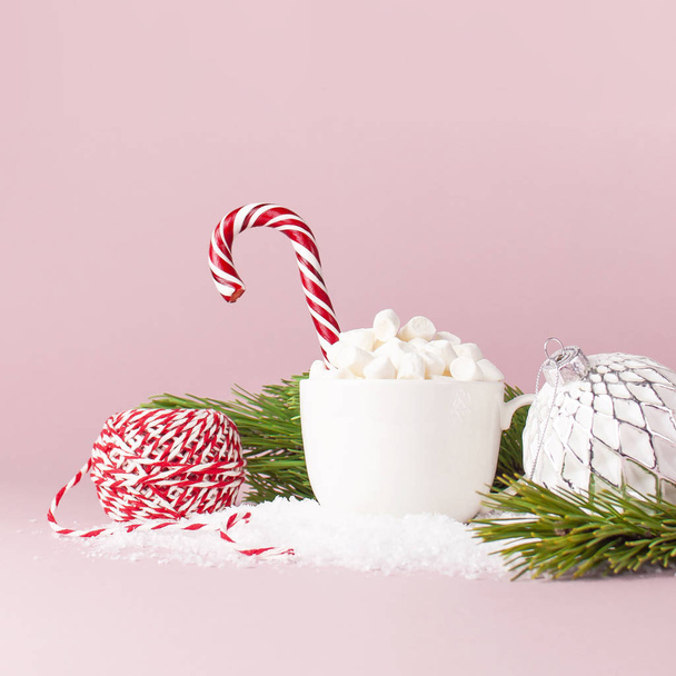 Karácsonyi-újévi ital, fehér bögre marshmallows, és cukorkát nád fenyő ágak labda, a rózsaszín háttér lapos feküdt másol hely hóban. Téli hagyományos italt élelmiszer ünnepség ünnepi dekoráció karácsony - Fotó, kép