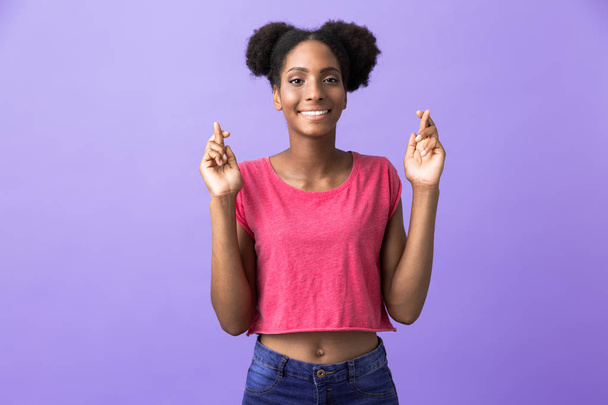 Photo d'une jeune femme afro-américaine souriante et gardant les doigts croisés isolés sur fond violet
 - Photo, image