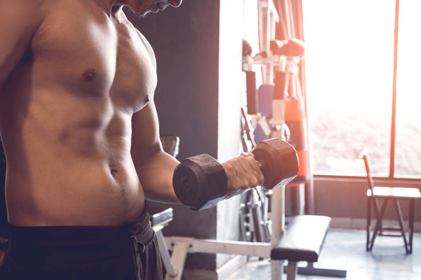 musculoso constructor asiático hombre entrenamiento su cuerpo con levantamiento dumbbell en derecho mano
. - Foto, imagen