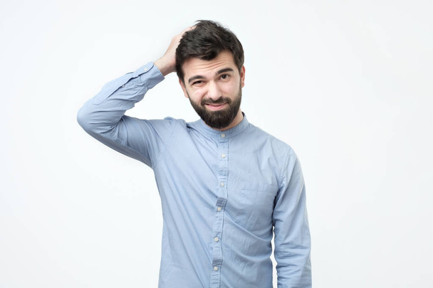 Jeune homme espagnol à la barbe noire réfléchissant, se grattant la tête
. - Photo, image