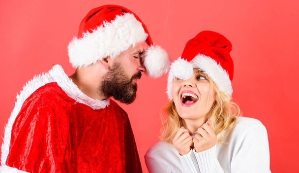 Man with beard and woman santa hat red background. Couple cheerful face celebrate christmas. Rent santa costume. Couple celebrate winter holiday christmas party. Christmas masquerade karnival concept - Photo, image