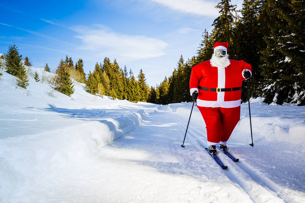 Babbo Natale con abiti natalizi con sci nordico classico in inverno innevato paesaggio sciistico di montagna nel giorno di sole, Capodanno o Natale sta arrivando
. - Foto, immagini