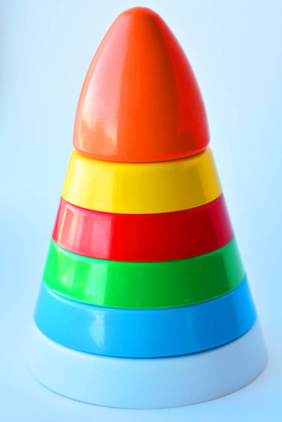 Детская игрушечная пирамида из разноцветных кругов на белом фоне
 - Фото, изображение