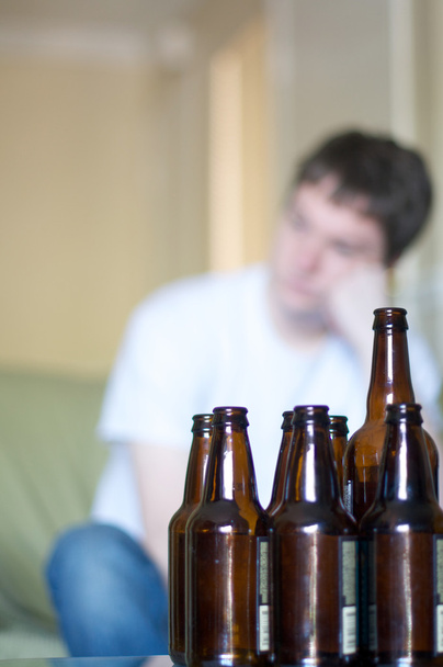 Vertical, hombre mirando a la izquierda con botellas de cerveza vacías
 - Foto, Imagen