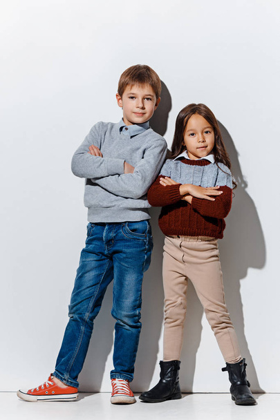 The portrait of cute little boy and girl in stylish jeans clothes looking at camera at studio - Фото, зображення