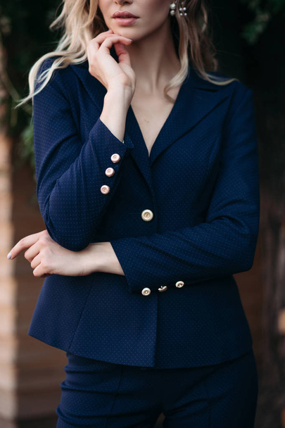 Elegant blonde woman in dark blue suit with gold buttons. - Фото, зображення