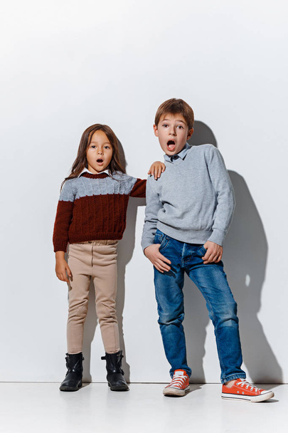 The portrait of cute little boy and girl in stylish jeans clothes looking at camera at studio - Foto, Bild