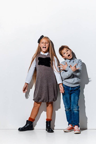 The portrait of cute little boy and girl in stylish jeans clothes looking at camera at studio - Фото, изображение
