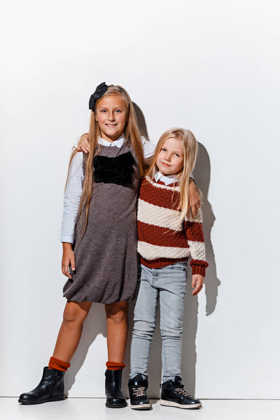 The portrait of cute little girls in stylish jeans clothes looking at camera at studio - Foto, Imagem