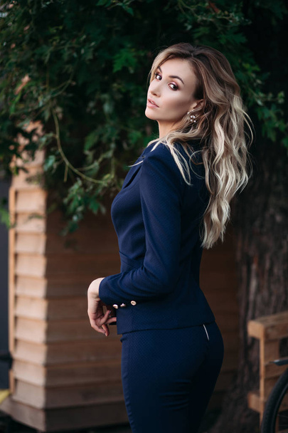 Elegant blonde woman in dark blue suit with gold buttons. - Фото, изображение