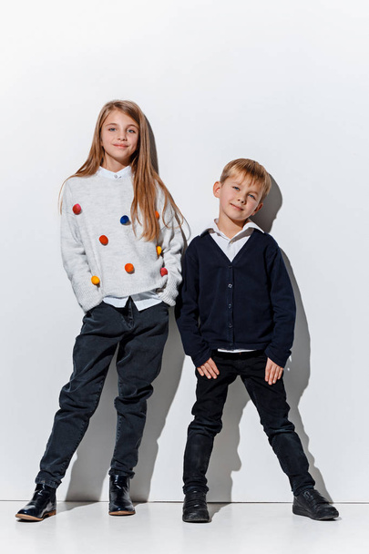 The portrait of cute little boy and girl in stylish jeans clothes looking at camera at studio - Fotó, kép