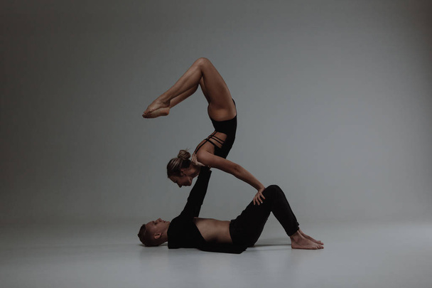 Two young modern ballet dancers posing over gray studio background - Фото, изображение