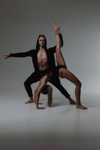 Two young modern ballet dancers posing over gray studio background - 写真・画像