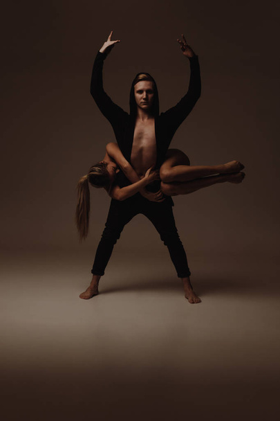 Two young modern ballet dancers posing over gray studio background - Photo, image