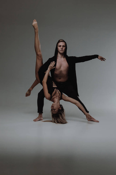 Two young modern ballet dancers posing over gray studio background - Photo, Image
