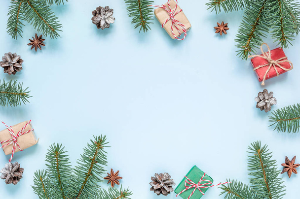 Weihnachtskomposition. Rahmen aus Tannenzweigen, Sternanis, Dekorationen, Geschenkschachteln und Tannenzapfen auf blauem Hintergrund. Weihnachten im Hintergrund. flach lag. Ansicht von oben mit Kopierraum - Foto, Bild