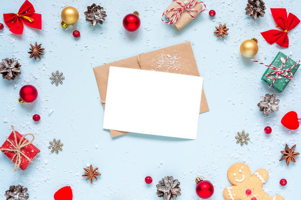 Χριστούγεννα ευχετήριας κάρτας στο πλαίσιο κατασκευασμένο από διακοσμήσεις Χριστουγέννων, κόκκινα μούρα, κουτιά δώρων και κουκουνάρια σε μπλε φόντο. Χριστούγεννα με φόντο. Επίπεδη θέσει. το Top view με αντίγραφο χώρου - Φωτογραφία, εικόνα