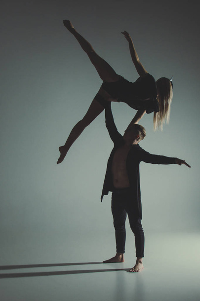 Two young modern ballet dancers posing over gray studio background - 写真・画像
