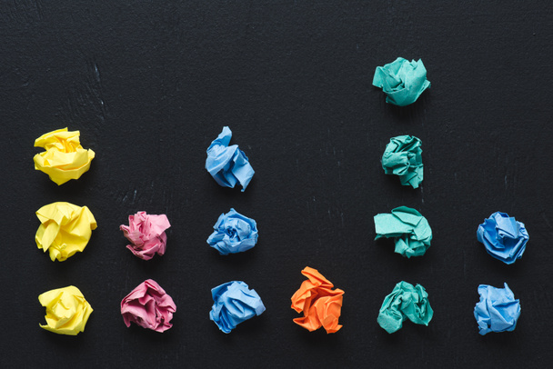 top view of arranged colorful crumpled paper balls on black background, think different concept - Foto, imagen