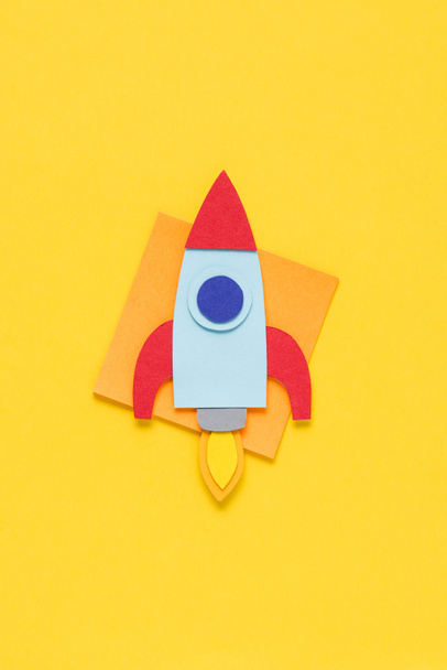 top view of flying paper rocket on yellow background, setting goals concept - Foto, Imagem