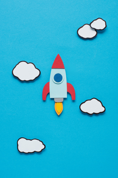 top view of paper rocket with clouds on blue background, setting goals concept - Photo, Image