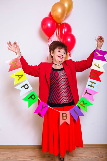 Mujer mayor celebración cumpleaños fiesta globos sobre un fondo blanco
 - Foto, imagen